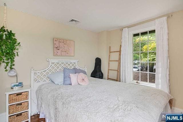 bedroom with visible vents, baseboards, and wood finished floors