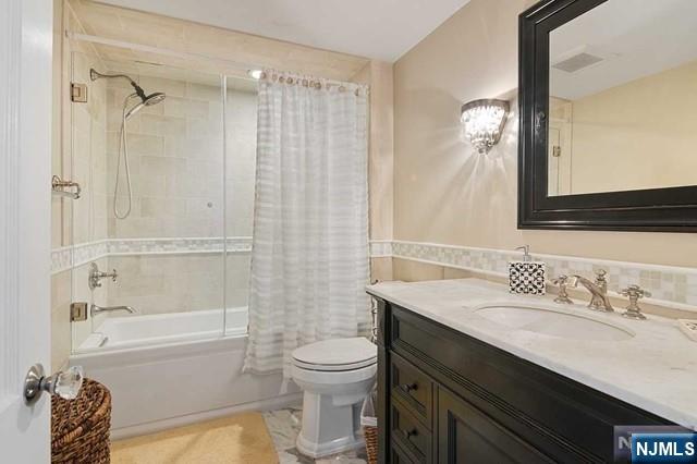 full bath featuring toilet, shower / bath combo, and vanity