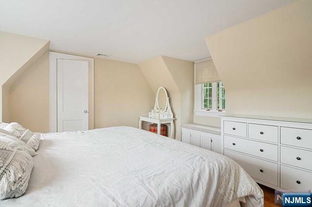bedroom featuring visible vents, wood finished floors, and lofted ceiling