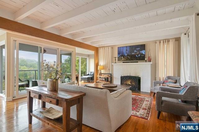 living area with beamed ceiling, wooden ceiling, wood finished floors, and a fireplace