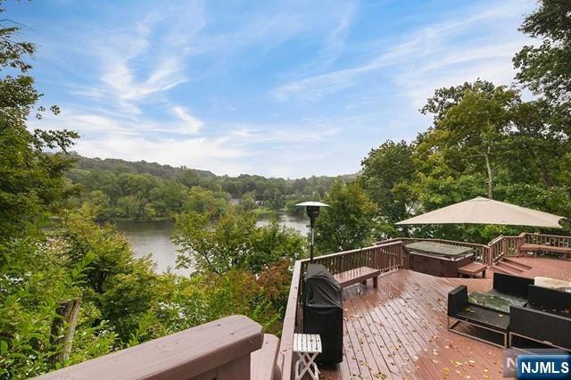 deck with grilling area, a forest view, and a water view