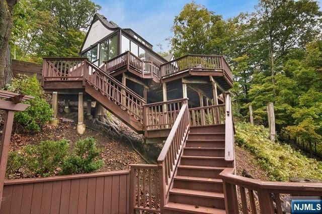 rear view of property featuring a standing seam roof, stairs, and a deck