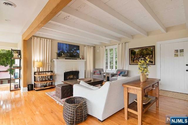 living room featuring visible vents, beamed ceiling, wood finished floors, and a fireplace