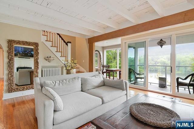living area with wood ceiling, beam ceiling, stairway, radiator, and hardwood / wood-style floors