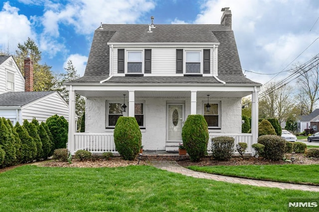 view of front of property with a front yard, a porch, stucco siding, and a shingled roof