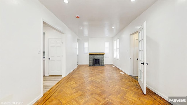 unfurnished living room with recessed lighting, a brick fireplace, and baseboards