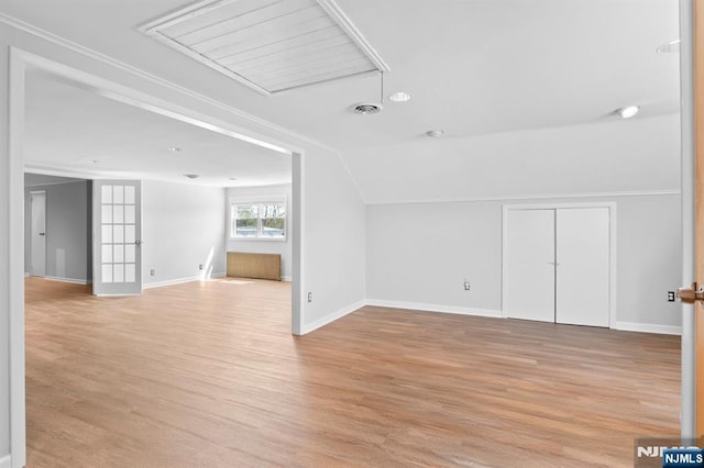 additional living space with vaulted ceiling, attic access, light wood-style floors, baseboards, and visible vents