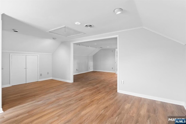 additional living space featuring lofted ceiling, attic access, baseboards, and light wood-type flooring