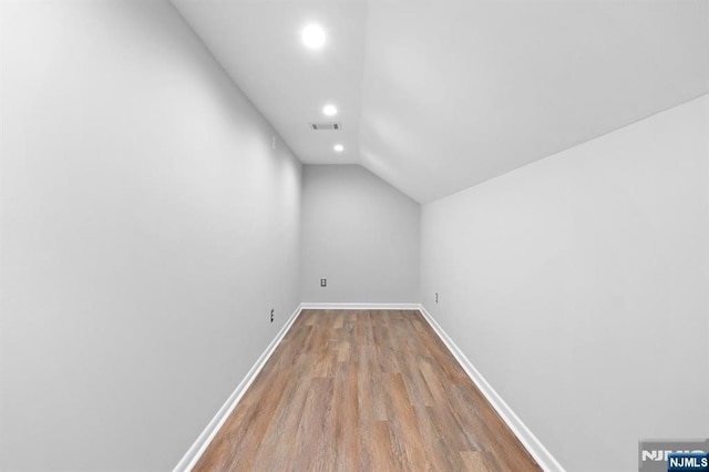 additional living space featuring vaulted ceiling, wood finished floors, baseboards, visible vents, and recessed lighting