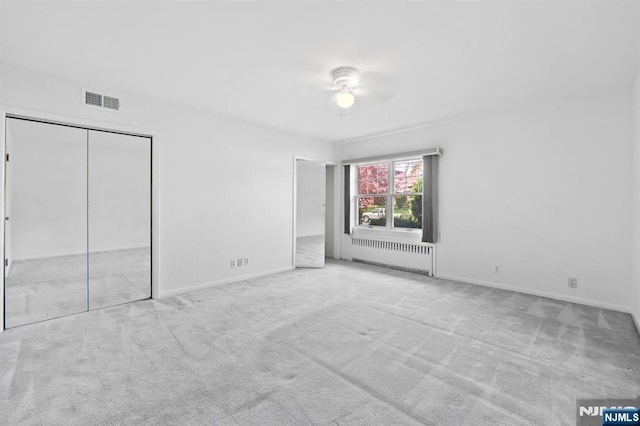 unfurnished bedroom with radiator heating unit, baseboards, visible vents, and carpet floors