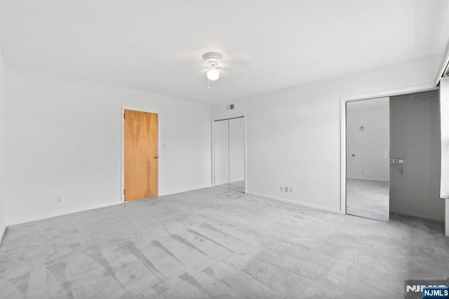 unfurnished bedroom with visible vents, a ceiling fan, carpet floors, baseboards, and two closets