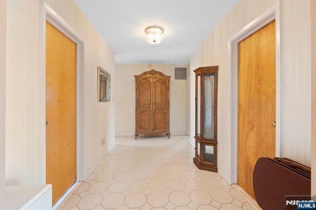 corridor featuring visible vents, baseboards, and light floors