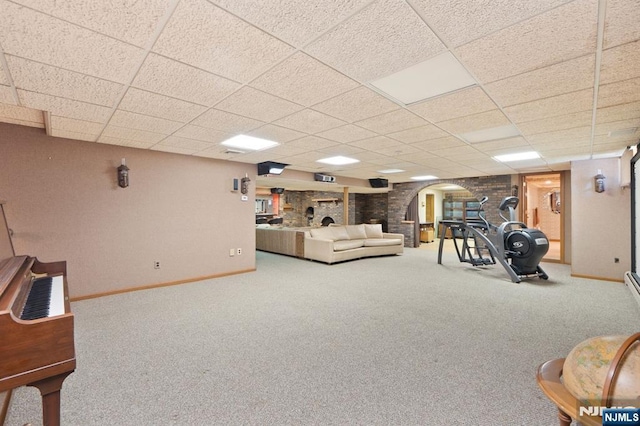 living area with arched walkways, carpet floors, a drop ceiling, and baseboards