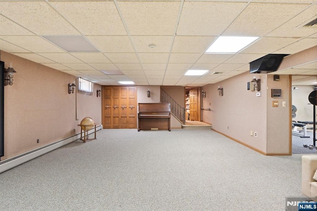finished basement with a paneled ceiling, stairs, carpet flooring, and baseboards
