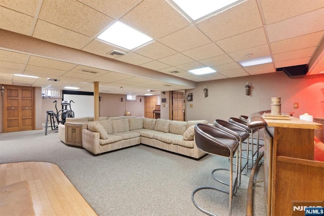 living area featuring a paneled ceiling, visible vents, and carpet flooring