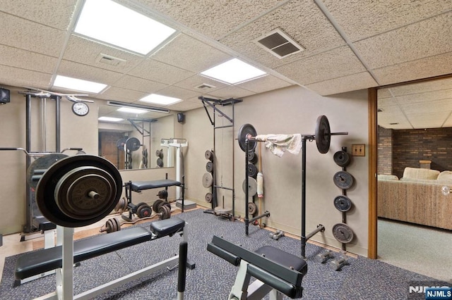 workout area with baseboards, visible vents, and a paneled ceiling