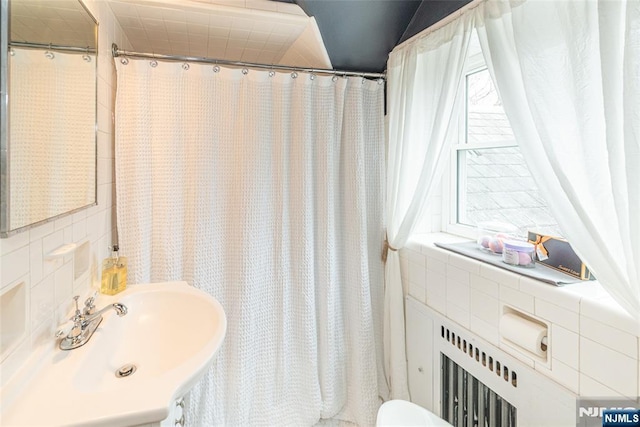 full bathroom featuring curtained shower, a sink, and tile walls