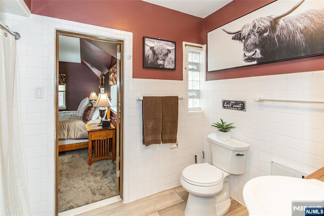 ensuite bathroom featuring tile walls, toilet, ensuite bathroom, and a shower with curtain