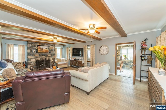 living area featuring ceiling fan, beam ceiling, light wood finished floors, and plenty of natural light