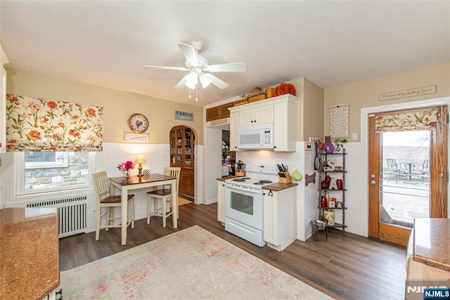 kitchen with arched walkways, dark wood finished floors, radiator heating unit, white appliances, and ceiling fan