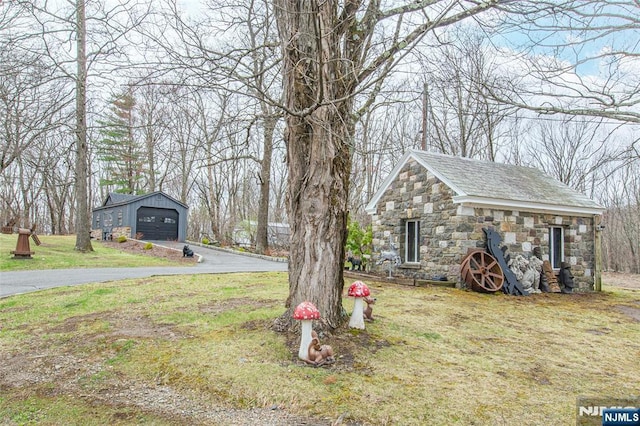 view of yard with an outdoor structure and aphalt driveway