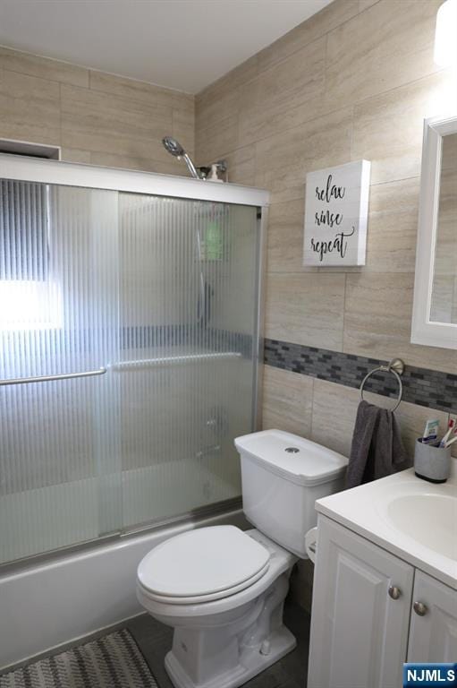 25 River Unit B10, Nutley, NJ 07110 - full bathroom with vanity, tile walls, backsplash, toilet, and shower / bath combination with glass door