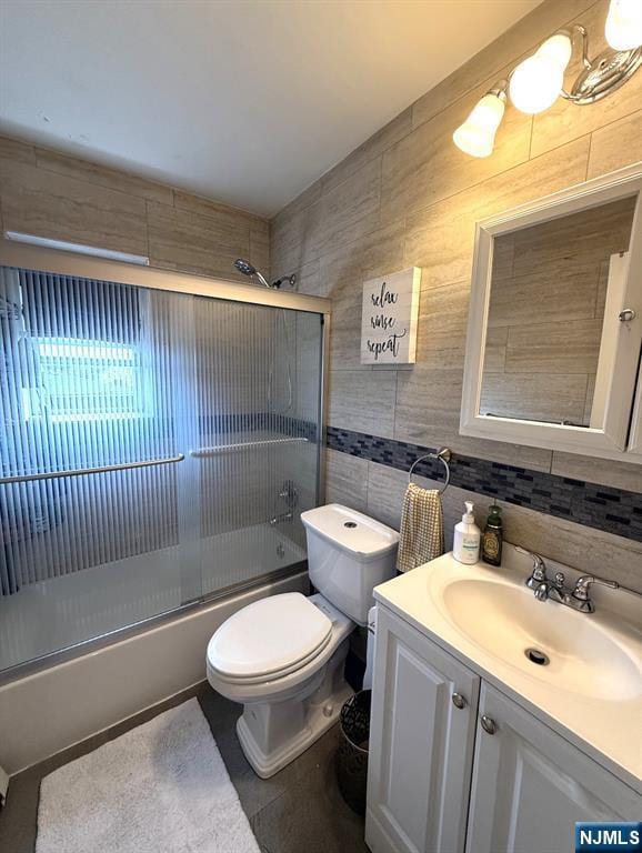25 River Unit B10, Nutley, NJ 07110 - bathroom featuring tile patterned floors, vanity, tile walls, bath / shower combo with glass door, and toilet