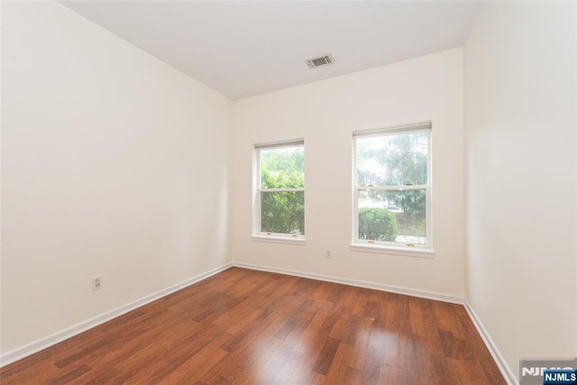 spare room featuring visible vents, baseboards, and wood finished floors