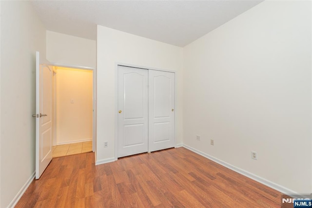 unfurnished bedroom with a closet, baseboards, and wood finished floors