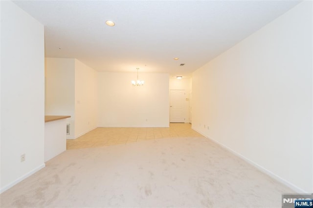 unfurnished room featuring a chandelier, light carpet, baseboards, and recessed lighting