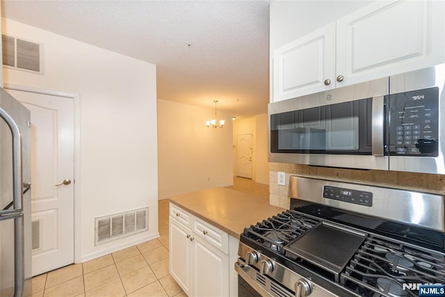 kitchen with stainless steel appliances, a notable chandelier, visible vents, and white cabinetry