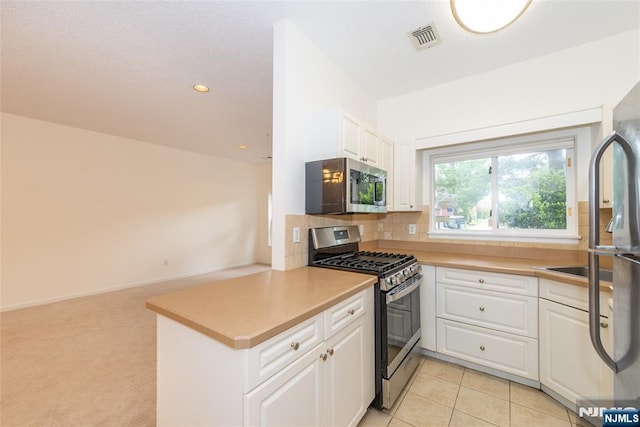 kitchen featuring white cabinets, appliances with stainless steel finishes, light countertops, and visible vents