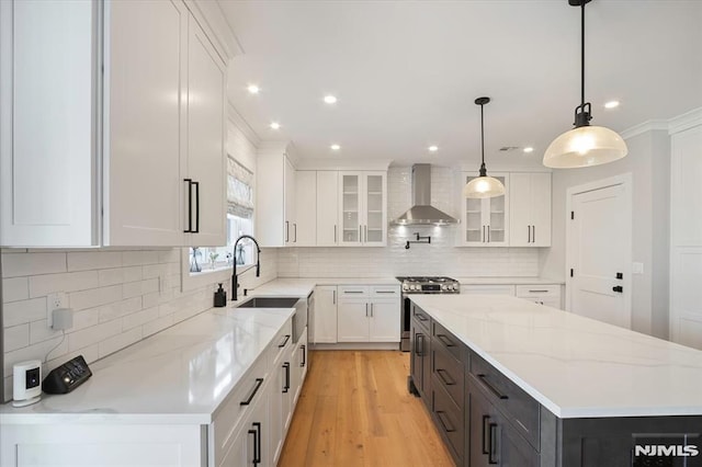 133 Graham Ter, Saddle Brook, NJ 07663 - kitchen with wall chimney exhaust hood, stainless steel gas range oven, a kitchen island, white cabinetry, and light wood-type flooring