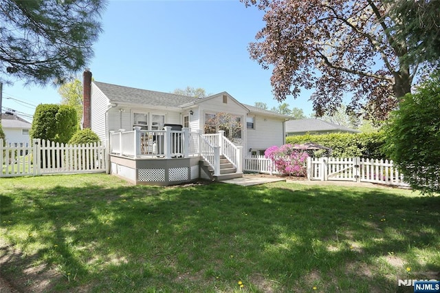 back of property with a chimney, a lawn, a wooden deck, a gate, and fence private yard
