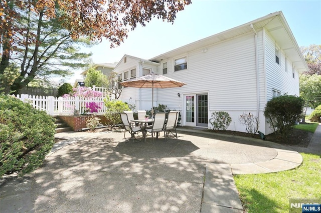 rear view of property featuring a patio, fence, and outdoor dining space