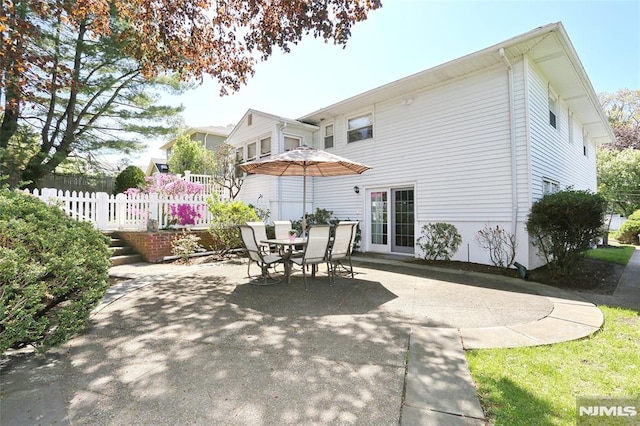 rear view of house featuring a patio, outdoor dining area, and fence