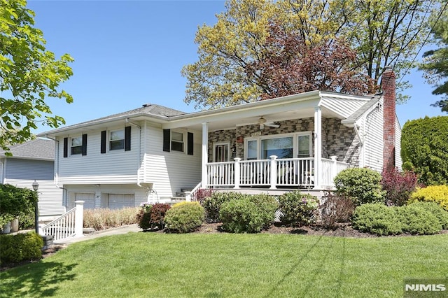 tri-level home with a porch, an attached garage, a chimney, and a front yard