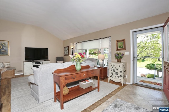 living area featuring plenty of natural light, baseboards, and lofted ceiling