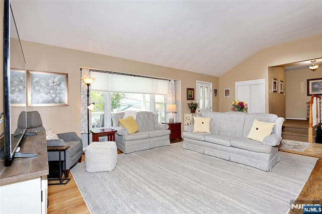 living room featuring light wood-type flooring, stairs, and lofted ceiling