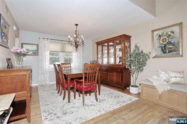 dining area with baseboards, light wood-style flooring, and a notable chandelier