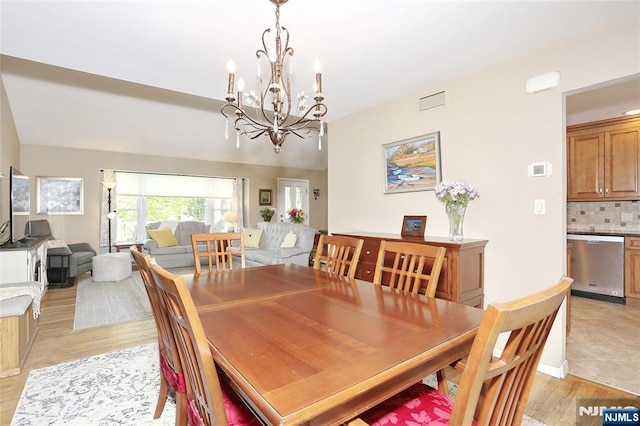 dining area with light wood-type flooring, a notable chandelier, and visible vents