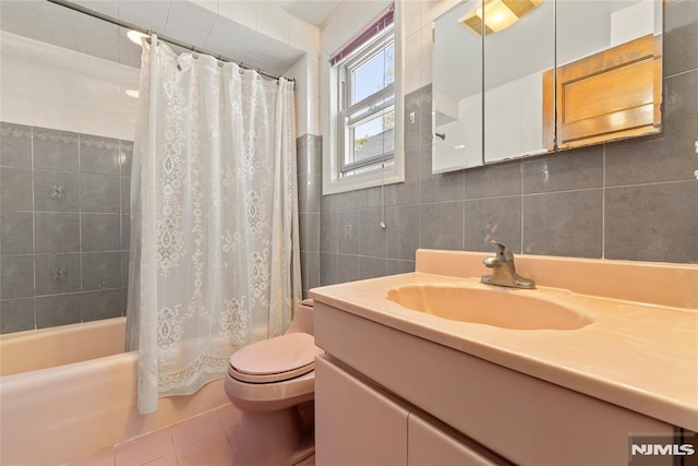 full bath with shower / bath combo, vanity, toilet, tile patterned floors, and tile walls
