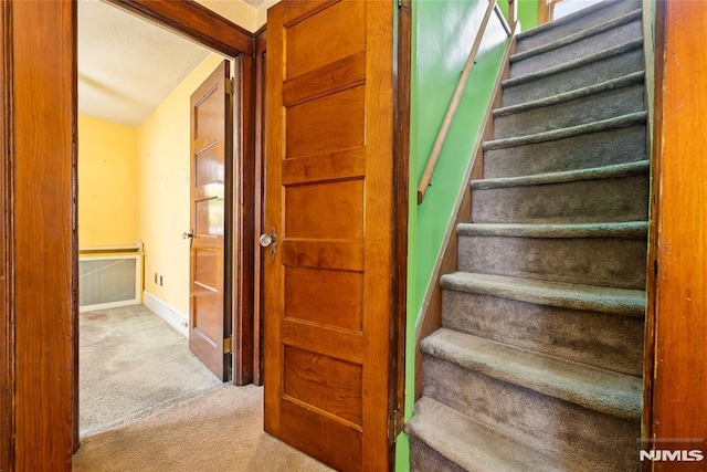 stairs featuring baseboards and carpet flooring