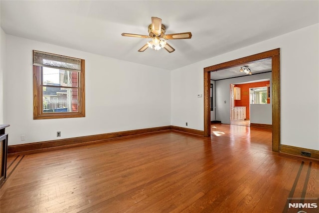 empty room with ceiling fan, plenty of natural light, baseboards, and hardwood / wood-style floors