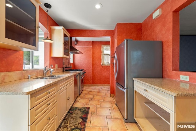kitchen with glass insert cabinets, stone finish floor, light stone counters, a sink, and appliances with stainless steel finishes