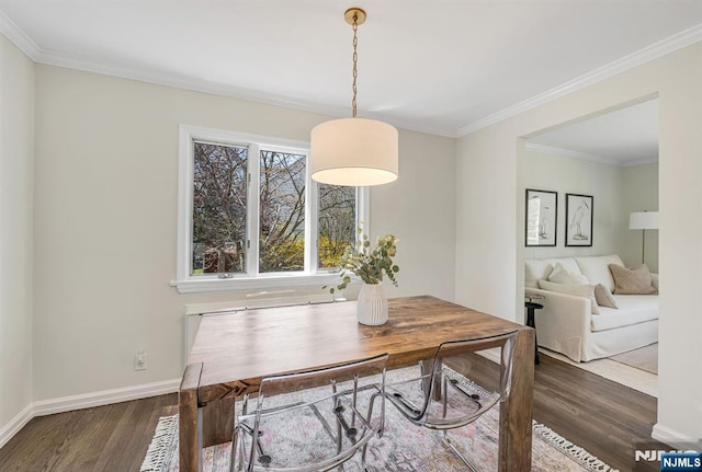 dining space featuring baseboards, crown molding, and wood finished floors