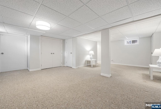 below grade area with carpet floors, a paneled ceiling, and baseboards