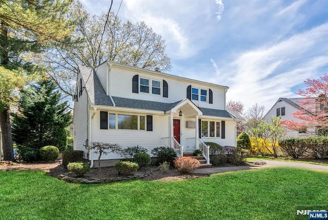 traditional-style home with roof with shingles and a front yard