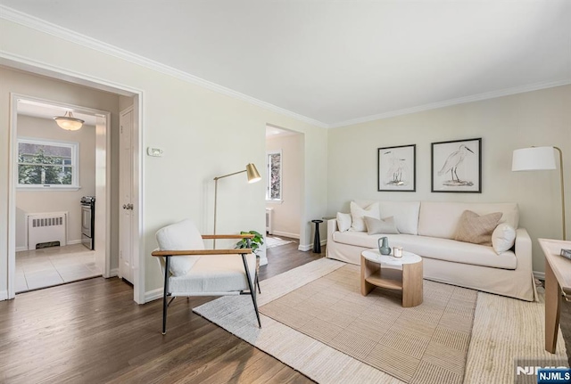 living room with crown molding, baseboards, radiator heating unit, and wood finished floors
