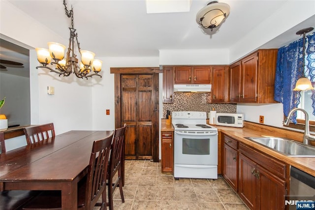 kitchen featuring under cabinet range hood, an inviting chandelier, a sink, white appliances, and decorative light fixtures